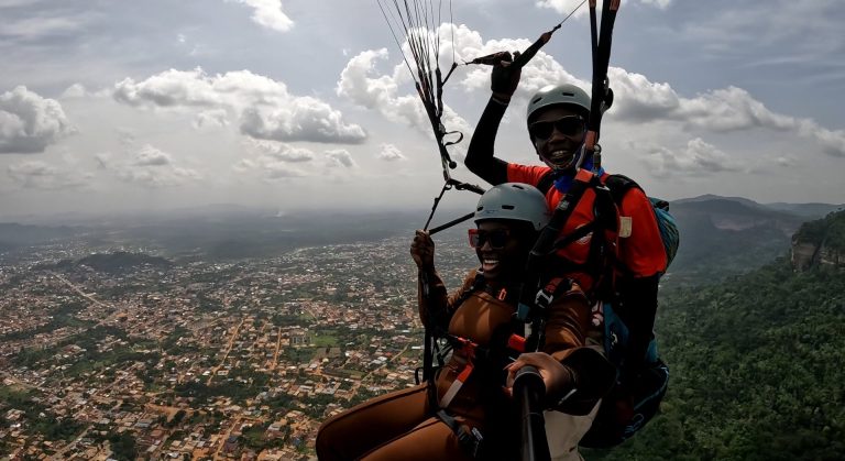 A paragliding pilot and passenger high above the Kwahu Plateau