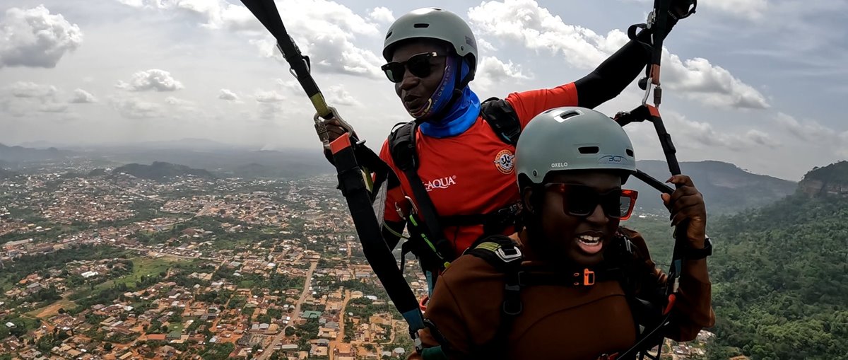 A tandem paragliding flight above the Kwahu Plateau, with the town far below
